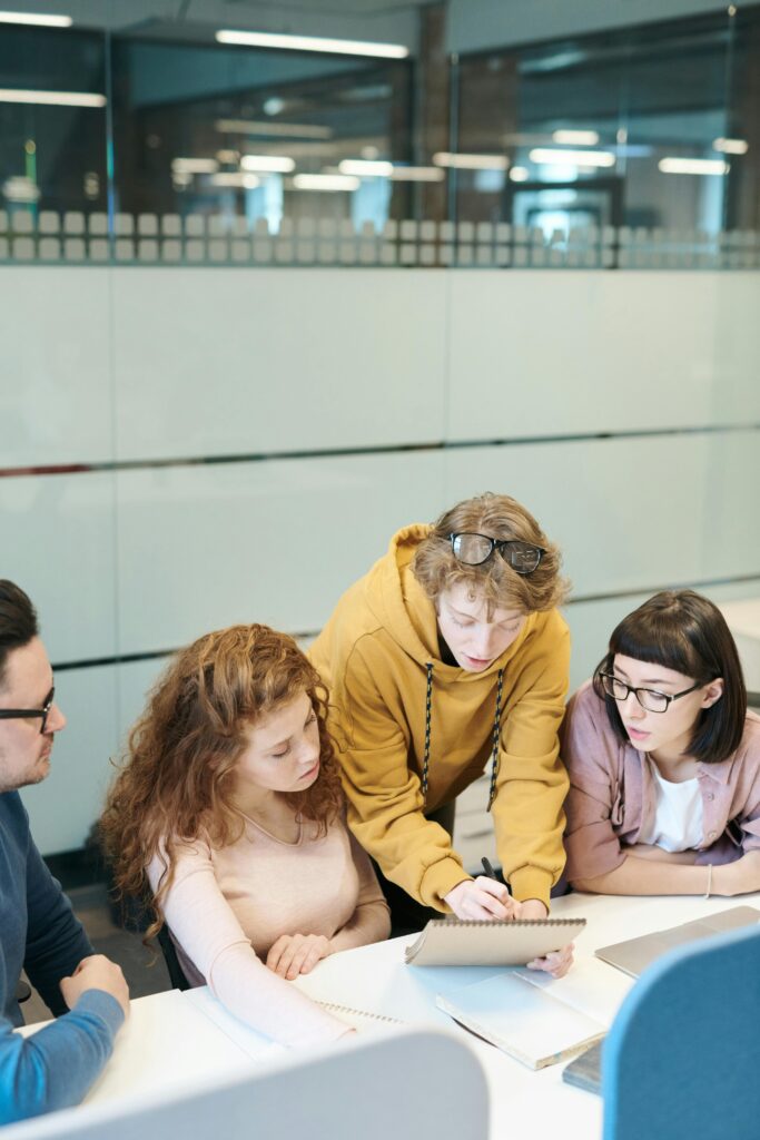 A group of young professionals working together at a modern office with teamwork and discussion dynamics.